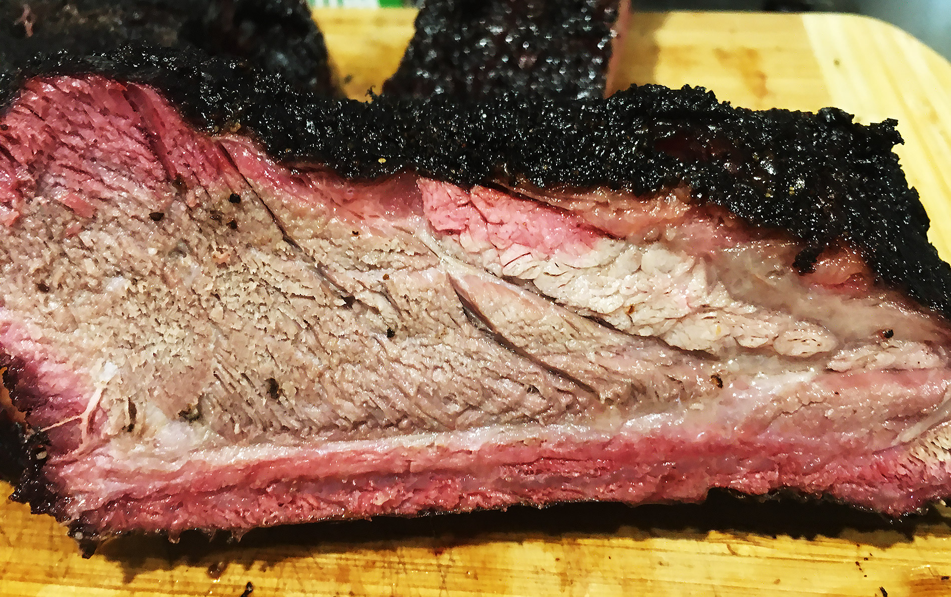 A failed early brisket — thick burnt bark over dry, grey meat