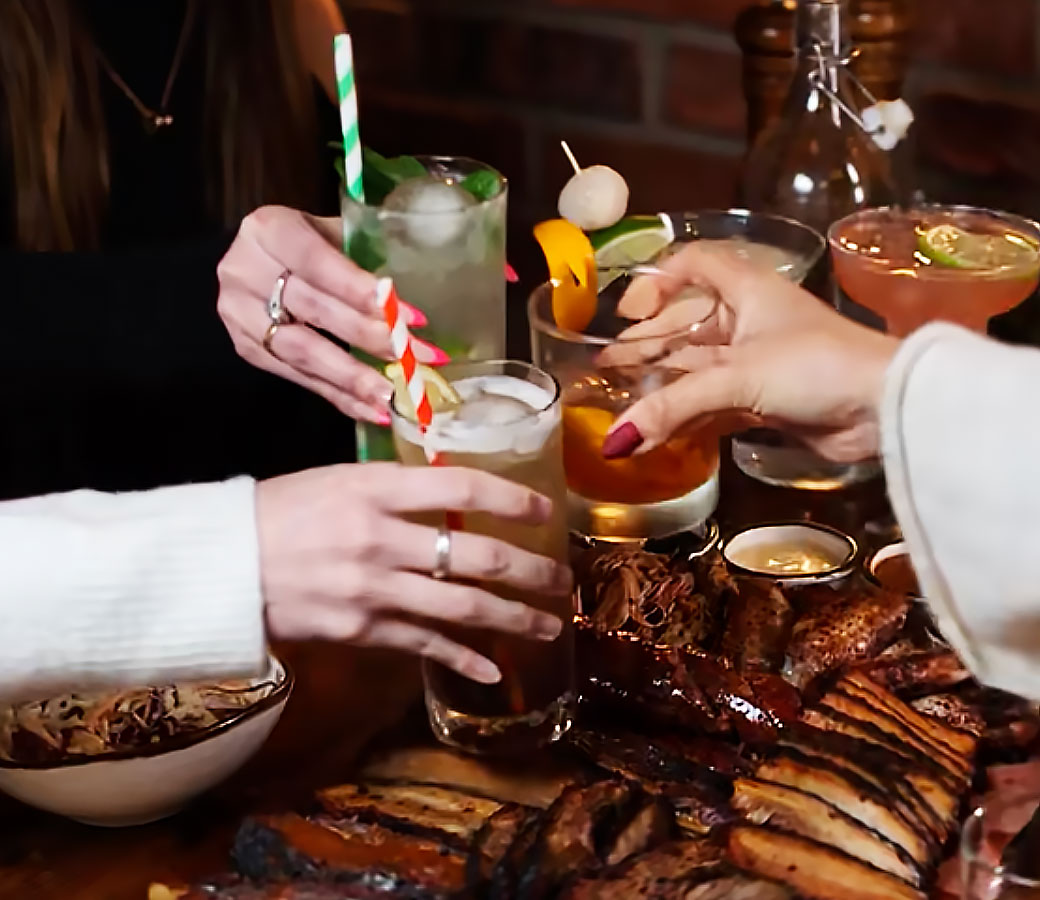 Friends raising drinks over a loaded BBQ platter