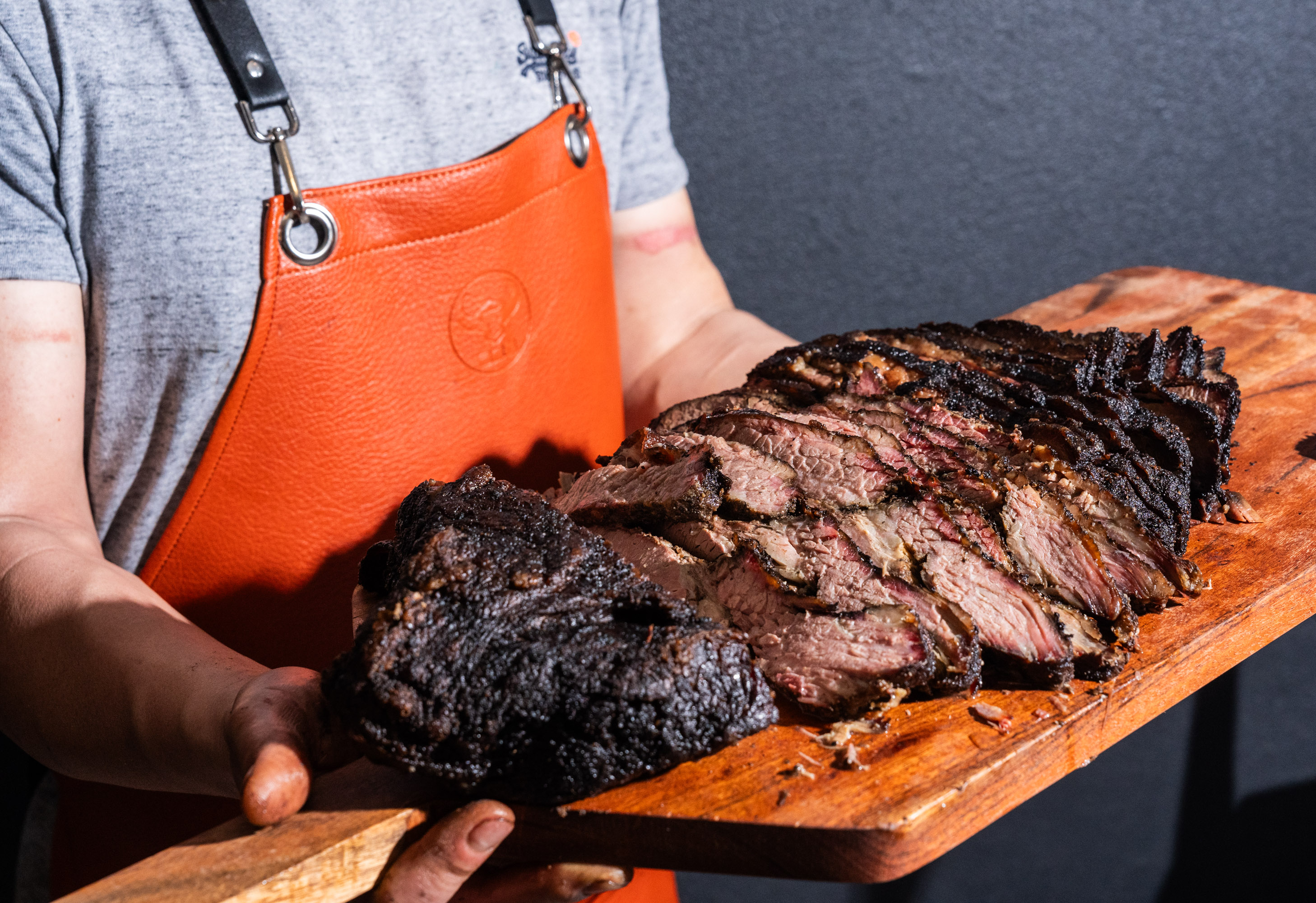 A brisket presented on butcher paper with sauces served beside it