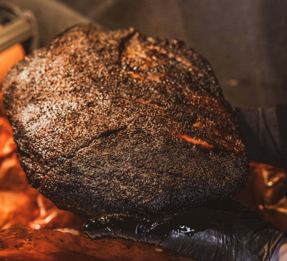 A whole brisket in the smoker, bark set dark